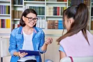 A high school girl talking to a smiling guidance counselor.