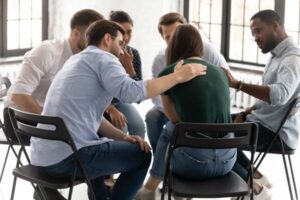 Attendees of a group counseling session comforting each other