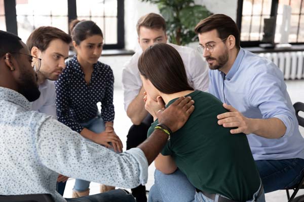 A group therapy session comforting a woman